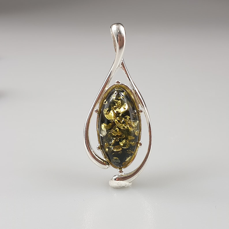 May include: A silver pendant with a green and gold amber stone in an oval shape.