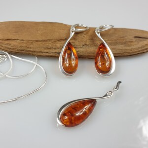 May include: A set of amber earrings and a pendant necklace with silver settings. The amber is a warm, honey color and the silver is polished.