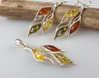 May include: A set of silver earrings and a pendant featuring a leaf design with amber stones in shades of green, yellow, and orange.