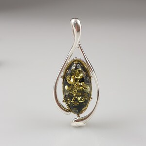 May include: A silver pendant with a green and gold amber stone in an oval shape. The pendant is in the shape of a teardrop.