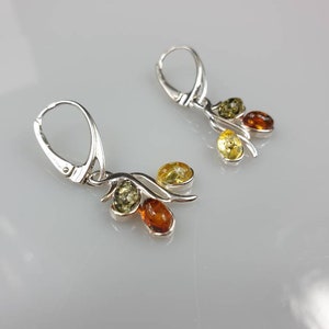 Op de afbeelding: Zilveren oorhangers met drie amberstenen in tinten geel, groen en oranje.