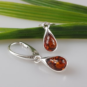 Puede incluir: Pendientes de plata de ley en forma de lágrima con piedras de ámbar. Los pendientes tienen un cierre de gancho y están marcados con "925" en la parte posterior.