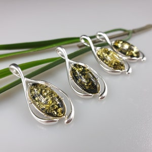 May include: Four silver pendants with green amber stones. Each pendant is shaped like a teardrop and has a twisted design.