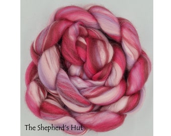 Puede incluir: Primer plano de una trenza de lana rosa, blanca y roja. La lana está dispuesta en forma circular, asemejándose a una flor.