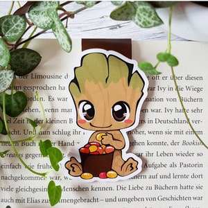 Può includere: Un personaggio dei cartoni animati con la pelle verde e grandi occhi tiene un secchio pieno di caramelle colorate. Il personaggio è un personaggio immaginario popolare dell'Universo Cinematografico Marvel.