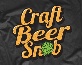 Puede incluir: Camiseta negra con el texto "Craft Beer Snob" en naranja y una hoja de lúpulo verde.