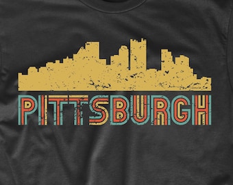May include: Black t-shirt with a vintage-style graphic of the Pittsburgh skyline and the word "PITTSBURGH" in colorful, retro-style lettering.