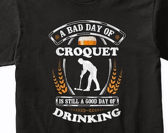 May include: Black t-shirt with a white graphic design that says "A bad day of croquet is still a good day of drinking". The graphic also includes a silhouette of a person playing croquet and a beer mug.