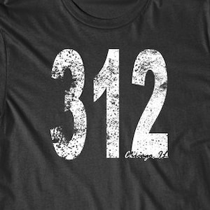 Puede incluir: Una camiseta negra con un gráfico blanco desgastado del número 312 y el texto "Chicago, IL".