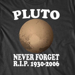Puede incluir: Camiseta negra con texto blanco que dice "Pluto Never Forget R.I.P. 1930-2006". Una imagen marrón y blanca de Plutón está centrada en la camiseta.