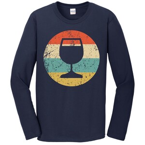 May include: Navy blue long-sleeve t-shirt with a vintage-style graphic of a wine glass in a circle with red, yellow, and blue stripes.