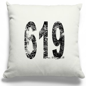 May include: A square, off-white throw pillow with the number "619" printed in large, distressed black font. The text "San Diego CA" is printed below the numbers in a smaller font.