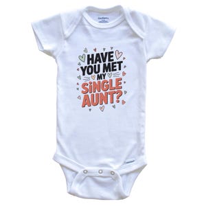 Puede incluir: Body de bebé blanco con el texto "HAVE YOU MET MY SINGLE AUNT?" en negro y rojo, rodeado de pequeños corazones. El body tiene mangas cortas y cierres de presión.