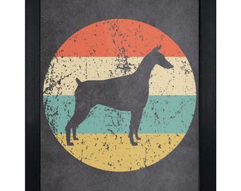 May include: A framed wall art piece featuring a dark gray silhouette of a Doberman dog centered within a circular graphic. The circle contains horizontal stripes of orange, cream, teal, and yellow with a distressed, weathered texture throughout.