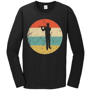 May include: A black long-sleeve t-shirt with a vintage-style graphic of a person playing the flute. The graphic is a circle with a red, orange, yellow, blue, and green color scheme.