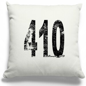 May include: White throw pillow with a black distressed graphic of the number 410 and the text "Baltimore, MD".