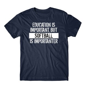 May include: A navy blue short-sleeved t-shirt featuring white distressed-style text that reads: EDUCATION IS IMPORTANT, BUT SOFTBALL IS IMPORTANTER. The word SOFTBALL is highlighted within a solid white rectangular block on the chest.