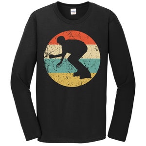 May include: A black long-sleeve t-shirt with a vintage-style graphic of a person rollerblading in a red, yellow, blue, and green circle.
