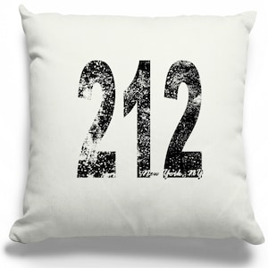 May include: White throw pillow with black distressed text that reads "212 New York, NY".