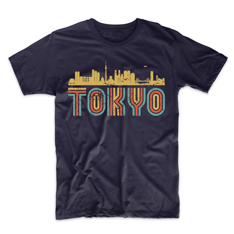 May include: A navy blue t-shirt with a vintage-style graphic of the Tokyo skyline and the word "TOKYO" in colorful, striped letters.