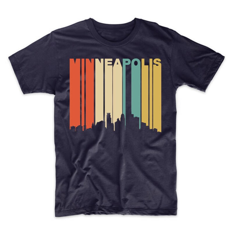 May include: A navy blue t-shirt featuring a vintage-style graphic of the Minneapolis skyline. The graphic has a multi-coloured striped background with the word "MINNEAPOLIS" in white letters.