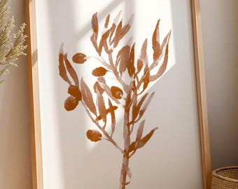 May include: A framed art print with a watercolour illustration of an olive branch in brown and orange hues. The artwork is set against a white backdrop within a light wood frame. The image is leaning against a wall.