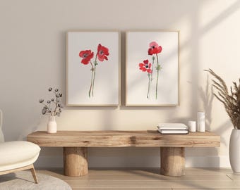 Può includere: Due stampe da parete incorniciate con illustrazioni ad acquerello di fiori di papavero rossi con steli verdi su sfondo bianco. Le stampe sono esposte in cornici di legno chiaro, posizionate fianco a fianco su una parete.