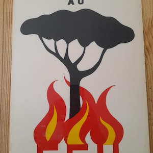 Pu&ograve; includere: Un cartello bianco con testo nero che recita "ATTENTION AU FEU". Il cartello presenta una silhouette di albero nero con fiamme rosse e gialle in basso, che avverte del fuoco.