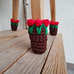 Puede incluir: Protectores de patas de silla de ganchillo con diseño de pudín de Navidad. Las fundas son marrones con detalles verdes y rojos, que recuerdan al acebo y a las bayas. Están diseñadas para adaptarse a las patas de una silla de madera, protegiendo el suelo de arañazos.