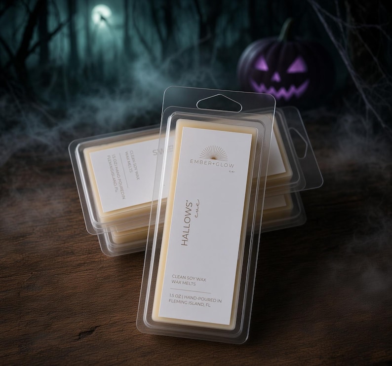 May include: A stack of clear plastic clamshell containers holding light beige soy wax melts. The white label features the text Ember + Glow, Hallows' Eve, Clean Soy Wax Wax Melts, and 1.5 oz Hand-Poured in Fleming Island, FL in black font.