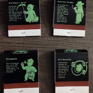 May include: Four black and red matchbox covers with green text and illustrations. The covers feature the Fallout logo and the names of four perks: Grim Reaper's Sprint, Mysterious Stranger, Pyromaniac, and Wild Wasteland.