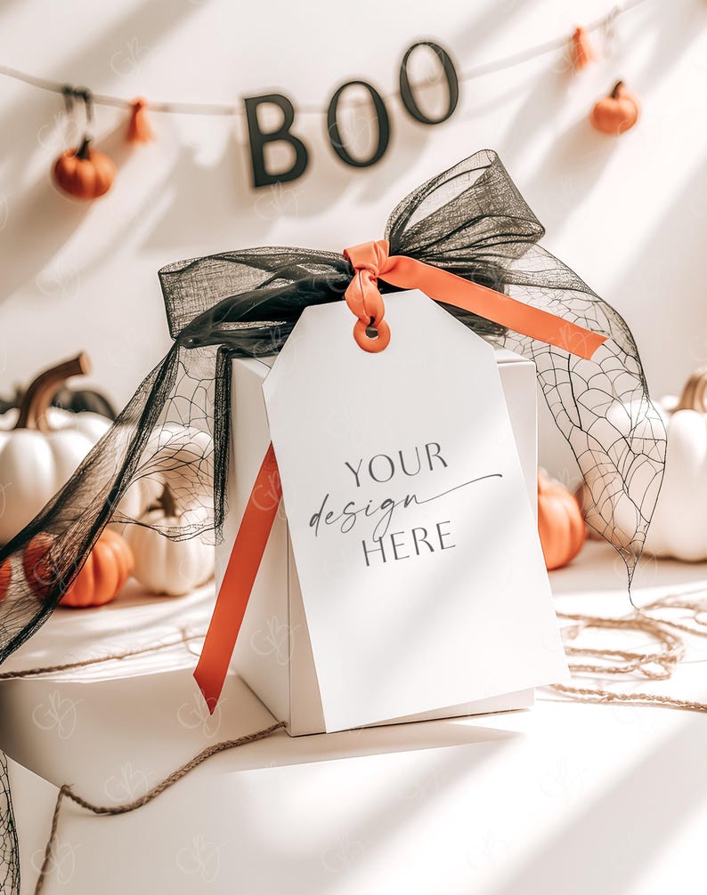 May include: A white gift box with a black and orange ribbon and a tag that says "YOUR design HERE". The box is surrounded by small white pumpkins and a string of orange pumpkins with a "BOO" banner.