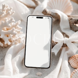 Op de afbeelding: Een gouden smartphone met een wit scherm ligt op een witte stof met schelpen en drijfhout. De tijd op het scherm is 9:41.