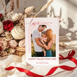May include: Valentine's Day card with a family photo inside a pink arch. The word "love" is written in red script above the photo. Below the photo, the text reads "Happy Valentine's Day" and "The Williams Family."