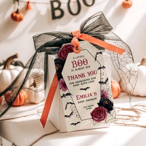 May include: A white gift box with a black and red Halloween themed gift tag. The tag says "A little Boo is almost due. Thank you for showering our baby with love. Emilia's Baby Shower Oct 24th 202X".