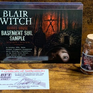 Peut inclure: Un &eacute;chantillon de terre du sous-sol de la maison Griggs de Blair Witch comprenant une carte de pr&eacute;sentation avec texte, un petit flacon en verre avec bouchon en li&egrave;ge contenant de la terre brune et un certificat d'authenticit&eacute; blanc num&eacute;ro 106049.