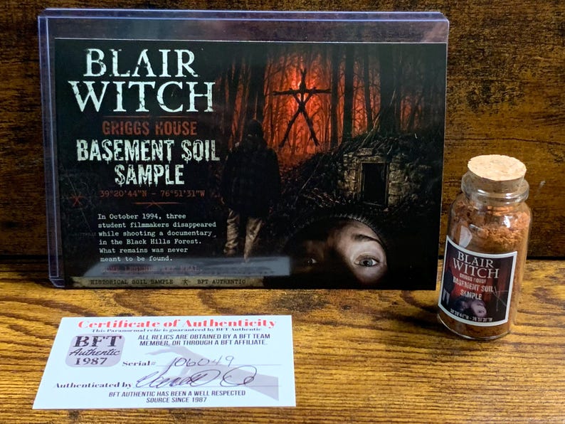 Peut inclure: Un &eacute;chantillon de terre du sous-sol de la maison Griggs de Blair Witch comprenant une carte de pr&eacute;sentation avec texte, un petit flacon en verre avec bouchon en li&egrave;ge contenant de la terre brune et un certificat d'authenticit&eacute; blanc num&eacute;ro 106049.