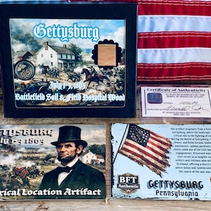 May include: A collection of Gettysburg artifacts, including a framed image of the battlefield, a wood sample, and a certificate of authenticity. The image features text: "Gettysburg July 1-3, 1863". Also included is a card with Abraham Lincoln.