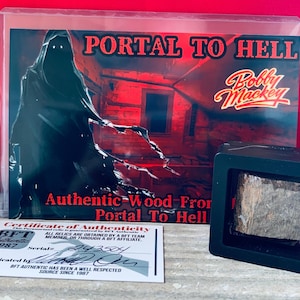 Könnte beinhalten: Ein schwarzer Rahmen mit einem Stück Holz aus dem "Portal zur Hölle" in einem schwarzen Rahmen mit einem Echtheitszertifikat von Bobby Mackey's Music World. Das Zertifikat ist datiert 1987 und hat die Seriennummer 243504.