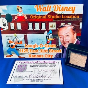Puede incluir: Un certificado de autenticidad para una reliquia de Walt Disney Laugh-O-Gram. El certificado es blanco con texto azul y rojo. Incluye el logotipo de BFT Authentic y un número de serie: 125637. El certificado está firmado por "Wusto Q".
