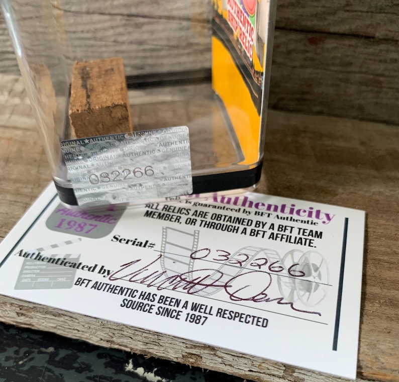 May include: A clear plastic display case with a brown wood piece inside. The case has a black label with the text "Authenticity" and "Serial# 032266". The label also includes the text "BFT Authentic has been a well respected source since 1987".