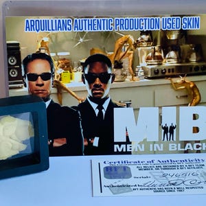 Puede incluir: Una exhibici&oacute;n con accesorios de la pel&iacute;cula "Men in Black". Incluye un trozo enmarcado de piel Arqullian, un certificado de autenticidad y una imagen promocional con el logotipo y los actores de la pel&iacute;cula.