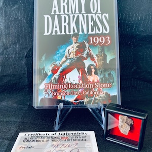 May include: A certificate of authenticity for a piece of rock from the filming location of the 1993 movie "Army of Darkness". The certificate is signed and numbered. The rock is in a small display case.