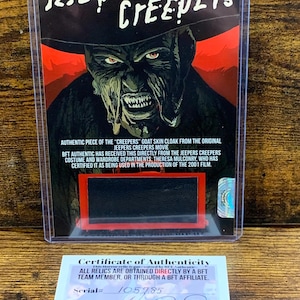 Peut inclure: Carte de collection avec l'affiche du film Jeepers Creepers. La carte comprend un morceau de la cape en peau de chèvre du film de 2001. Un certificat d'authenticité est inclus. Le numéro de série est 105785.