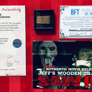 May include: A certificate of authenticity for a piece of wood from the movie Saw III. The certificate is signed by the producers, Mark Burg and Oren Koules. The certificate includes a photo of the wooden crate from the movie and a photo of the piece of wood. The certificate also includes a serial number and a signature. The certificate is framed and ready to be displayed.