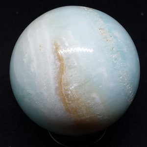 May include: A large, smooth, light blue and brown sphere made of polished stone. The sphere has a swirling pattern of light blue and brown.