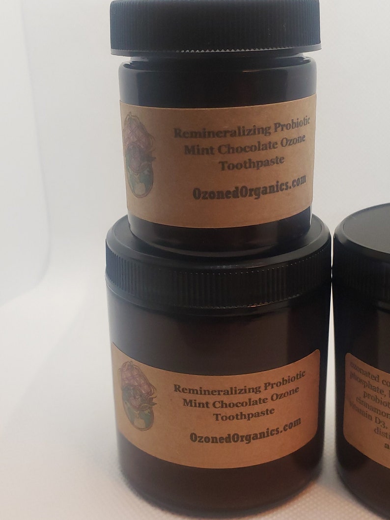 May include: Two brown glass jars with black lids containing remineralizing probiotic mint chocolate ozone toothpaste. The label on the jars reads "Remineralizing Probiotic Mint Chocolate Ozone Toothpaste" and "OzonedOrganics.com".