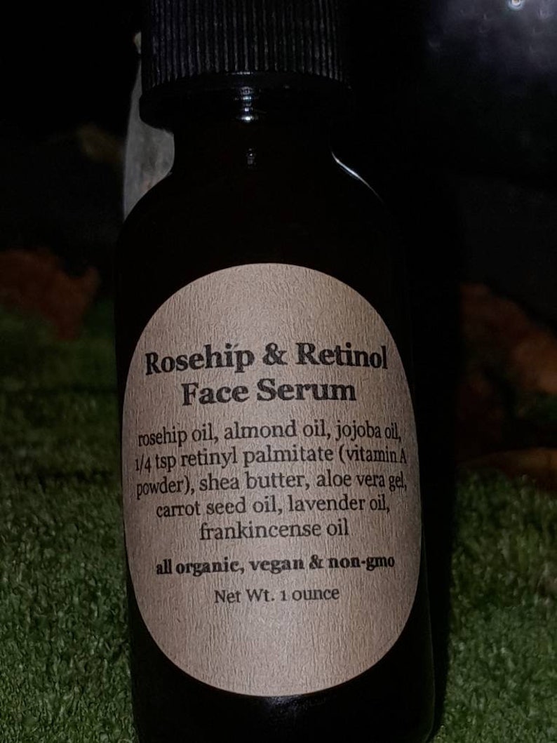 May include: A brown glass bottle with a label that reads "Rosehip & Retinol Face Serum". The label lists the ingredients: rosehip oil, almond oil, jojoba oil, 1/4 tsp retinyl palmitate (vitamin A powder), shea butter, aloe vera gel, carrot seed oil, lavender oil, frankincense oil. The label also states that the product is all organic, vegan & non-gmo. The bottle contains 1 ounce of serum.