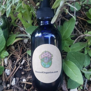 May include: A blue glass bottle with a dropper top and a brown label. The label has a graphic of a globe with a flower of life design and the text "OzonedOrganics.com".