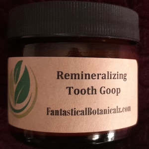 May include: A small brown glass jar with a black lid and a label that reads "Remineralizing Tooth Goop" and "FantasticalBotanicalz.com".